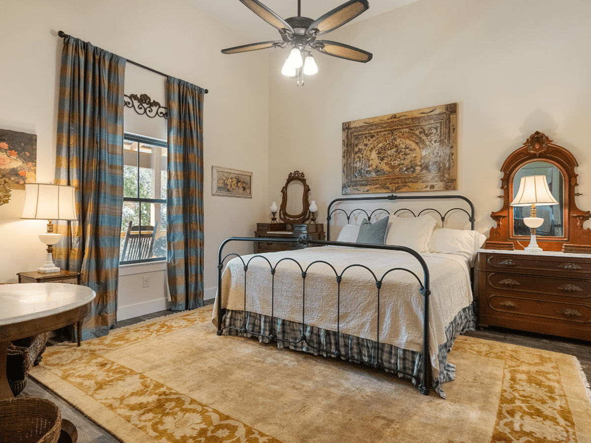 Image of king bed with iron frame white bedspread with view out window in texas hill country