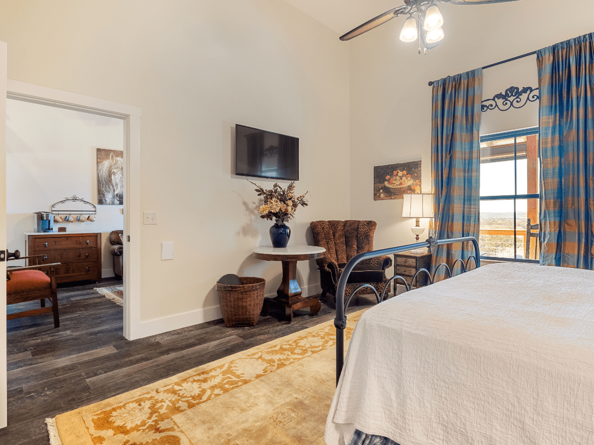 Image of white bedspread on king bed in hotel room overlooking texas hill country