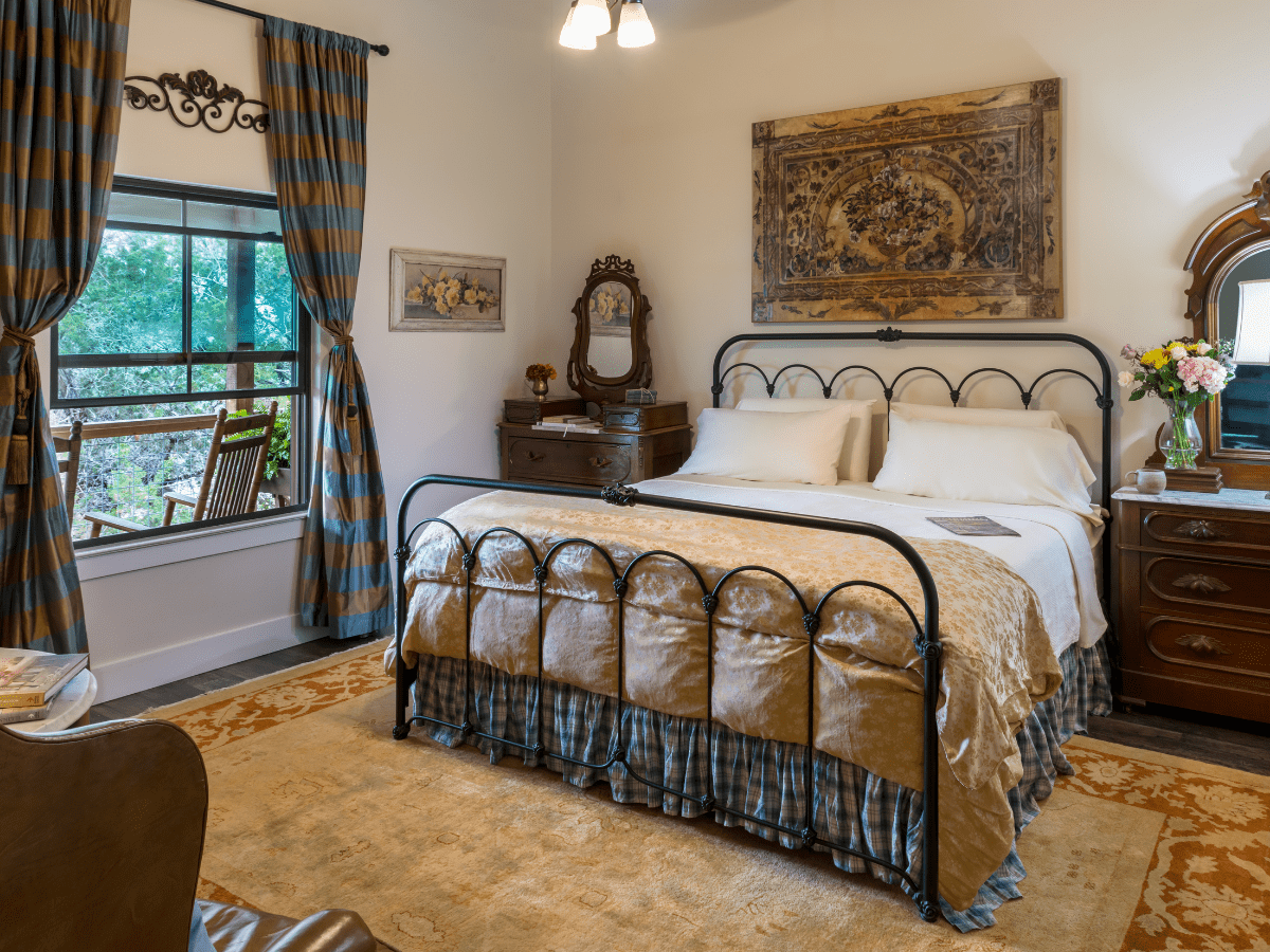 Inn_at_Sunset_Mill_Ranch_Wimberley_Hotel_sunset_room - Inn at Sunset Mill Ranch Image of king iron bed with picture window at Inn at Sunset mill Ranch in Wimberley texas